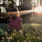 petite fille en forêt qui regarde le soleil